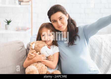Felice famiglia incinta madre e figlia che prendono selfie insieme Foto Stock