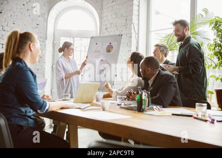 Per idee. Gruppo di giovani professionisti del business che hanno una riunione. Diversi gruppi di colleghi discutono nuove decisioni, piani, risultati, strategia. Creatività, lavoro, business, finanza, lavoro di squadra. Foto Stock