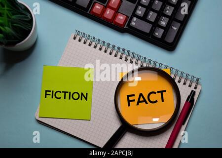 Narrativa e Fatto scrivere su una nota adesiva isolata sulla scrivania dell'ufficio. Foto Stock