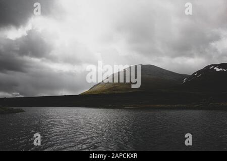 Lago di fronte alle montagne nuvolose Foto Stock