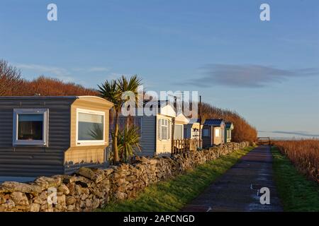 Una fila di Caravan statici nel Wairds Park di fronte alla spiaggia nel villaggio di pescatori di Johnshaven in una chiara, soleggiata mattina di gennaio Foto Stock