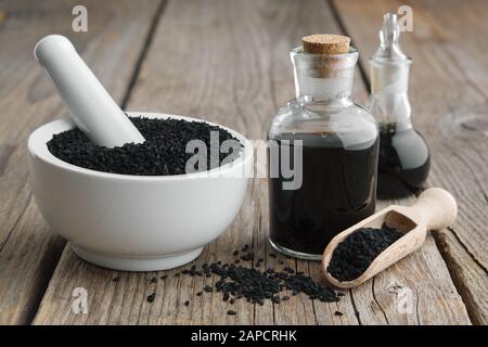 Semi di cumino nero o coriandolo romano e bottiglie di olio di cumino nero. Ingredienti per cucinare. Trattamenti ayurvedici. Foto Stock