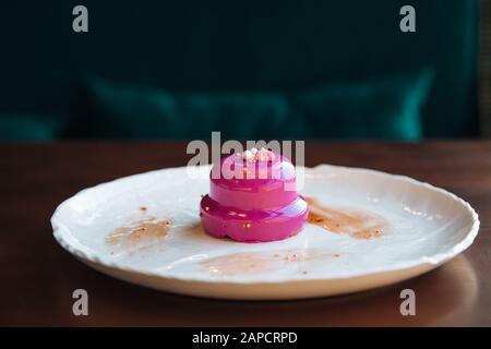 Torta rotonda con noci ripieno colato smalto di colore rosa. Su una piastra bianca, in piedi sulla tavola. Foto Stock