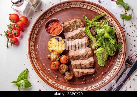 Vitello al forno servito con verdure alla griglia, funghi e salsa al peperoncino, piatto da ristorante, vista dall'alto, orientamento Orizzontale Foto Stock