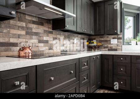 Mobili cucina scura e pietra backsplash Foto Stock