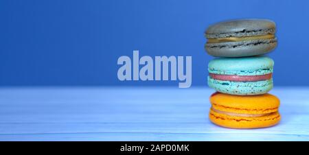 Macaroons colorati su sfondo blu classico, biscotti francesi come un regalo per la vacanza, spazio per il testo Foto Stock