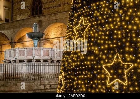 Perugia, Umbria, Italia. Il monumento principale della città, la Fontana maggiore, in Piazza IV Novembre, con luci di Natale e albero di Natale Foto Stock