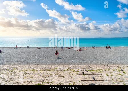 I turisti si rilassano sulla spiaggia di ciottoli nella Baia degli Angeli sulla Riviera Francese a Nizza, Francia. Foto Stock