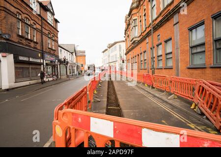 Lunga e stretta trincea scavata in una strada principale per la posa di tubi a Long Eaton, Derbyshire, Regno Unito Foto Stock