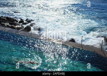 Un nuotatore lun lap presso la piscina dell'Oceano Bronte nella luce Del Mattino Foto Stock