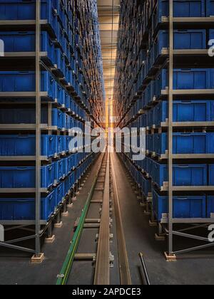 Scatole blu in un grande magazzino logistico completamente automatizzato scorrono su un nastro trasportatore. Ci sono molte posizioni di stoccaggio. E' un moderno sistema di realizzazione Foto Stock