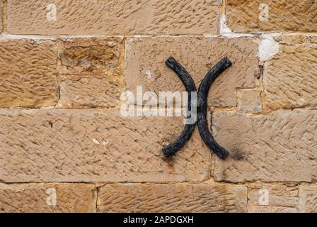 Richmond, Tasmania, Australia - 13 dicembre 2009: Closeup di tassello in metallo pesante nero muro in pietra marrone a storica prigione edificio. Foto Stock