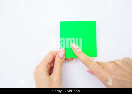 Office Hand Holding Un Adesivo A Colori Verde Su Sfondo Bianco. Copyspace. Posiziona per testo Foto Stock