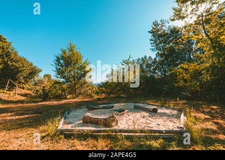 Ampio scatto di un parco con un fuoco in un sandbox circondato da piante e alberi Foto Stock