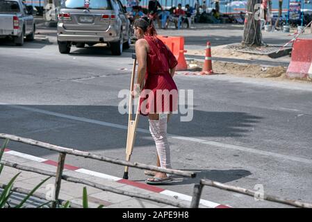 Stampelle donna: Camminare con l'aiuto di stampelle all'esterno Foto Stock