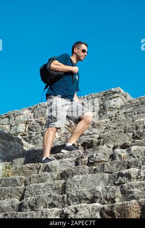 Turista che sale su una rovina Maya in Dzibilchaltun, Yucatan, Messico Foto Stock