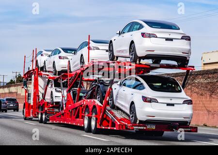 18 gennaio 2020 Palo Alto / CA / USA - il trasportatore di automobili trasporta i veicoli nuovi della Tesla Model 3 su una superstrada nell'area della baia di San Francisco, vista posteriore del rimorchio Foto Stock