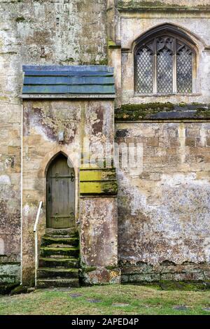 Vecchia porta di legno e gradini nella Chiesa di San Michele e Di Tutti gli Angeli. Withington, Gloucestershire, Inghilterra Foto Stock