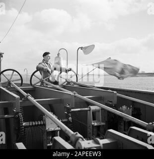 Navigazione sul Reno, reportage su come vivere e lavorare a bordo di una nave del Reno Descrizione: Membro dell'equipaggio Arthur ai freni della spiaggia, moedelijk nei Paesi Bassi Data: 1 aprile 1955 Parole Chiave: Fiumi, skipper, rimorchiatori Foto Stock