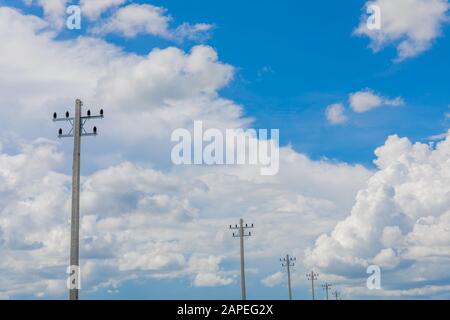 Palo elettrico in sfondo blu cielo e nube bianca. Foto Stock