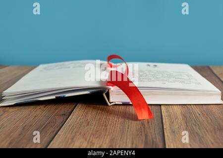 Un libro aperto si trova su una tabella con un segnalibro per le pagine. Rilegatura del libro. Conoscenza e istruzione. Libri per bambini. Foto Stock