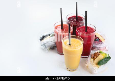 Frullati di frutta fresca e verdura Htalthy con ingredienti assortiti serviti in confezioni. Vista frontale con spazio di copia Foto Stock