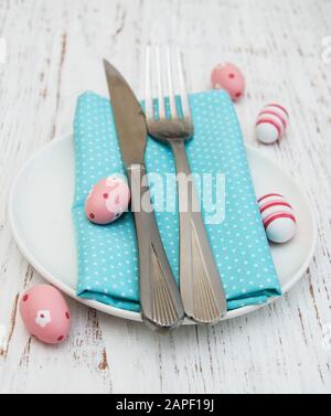 Preparazione del tavolo di Pasqua - uova di quaglia, piatto su un vecchio sfondo di legno bianco Foto Stock