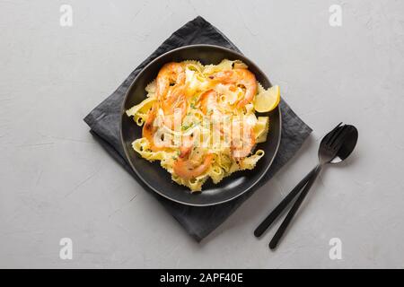 Pasta spaghetti reginette con frutti di mare, gamberi, cozze piatto nero su tavola grigia in cemento, primo piano. Piatto tradizionale in ristorante italiano a Milano Foto Stock