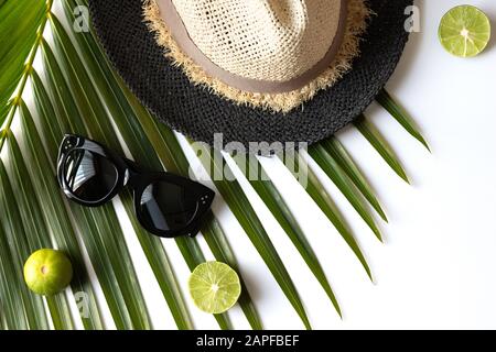 Composizione estiva con frutta, cappello e foglia di palma tropicale su sfondo bianco. Foto Stock