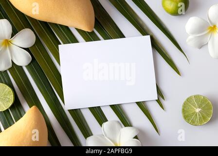 Modello estivo con biglietto d'auguri, frutta, foglia di palma tropicale e fiori su sfondo bianco Foto Stock