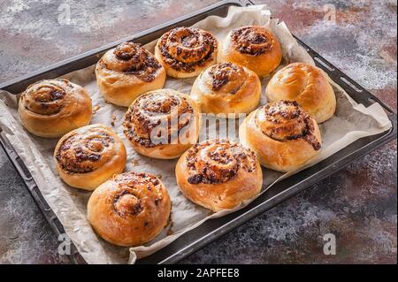 Dolci freschi dolci dolci dolci alla cannella con crema di cioccolato su una teglia da forno. Foto Stock