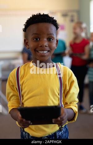 Schoolboy usando un computer tablet in una scuola elementare classe Foto Stock