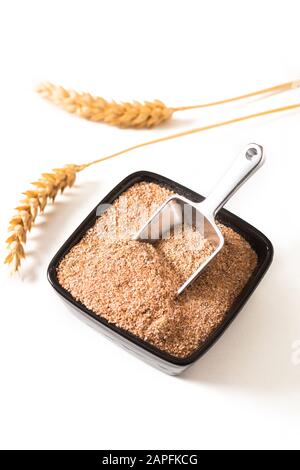 Concetto di cibo sano Crusca Di Grano Organico in tazza di ceramica nera con orecchio di grano isolato su sfondo bianco Foto Stock