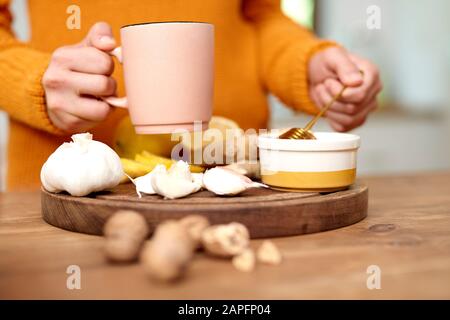 La mano della donna che tiene la tazza di tè caldo con miele Foto Stock