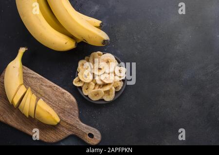 Disidratati, freschi e Banane essiccate chip su sfondo nero. Vista da sopra. Spazio di copia Foto Stock