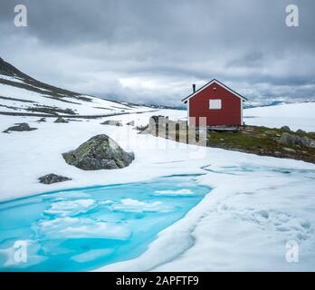 Tipica casa norvegese di legno rosso vicino alla famosa strada montana Aurlandsvegen (Bjorgavegen) in Aurland, Norvegia in estate. Fotografia di paesaggio Foto Stock