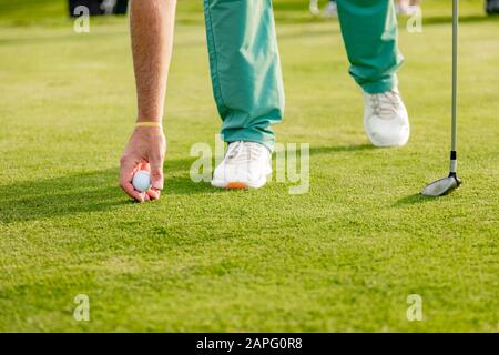 Uomo che mette la sfera di golf sul verde sul campo di golf Foto Stock