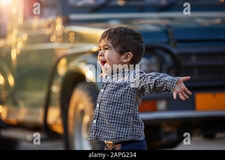 Bambino eccitato con braccia aperte in piedi da un grande veicolo Foto Stock