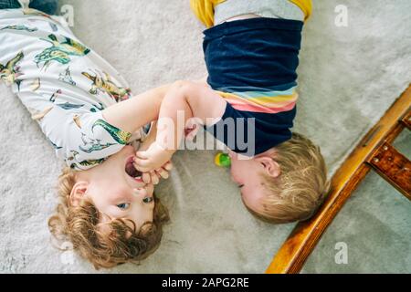 Fratelli che giocano sul tappeto a casa Foto Stock