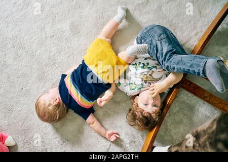 Fratelli che giocano sul tappeto a casa Foto Stock