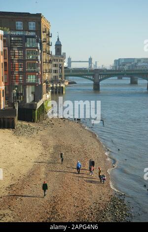 Persone che camminano lungo il percorso pedonale lungo il fiume Tamigi con bassa marea a Londra, Inghilterra, Regno Unito Foto Stock