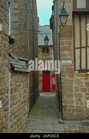 Stretto passaggio tra due edifici in pietra tradizionali con porta d'ingresso rossa davanti Foto Stock