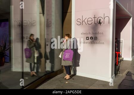 Una giovane donna tiene una conversazione telefonica privata in un angolo soleggiato vicino a 'Sketch', una gastro-galleria su Conduit Street, il 20th gennaio 2020, a Londra, Inghilterra. Foto Stock