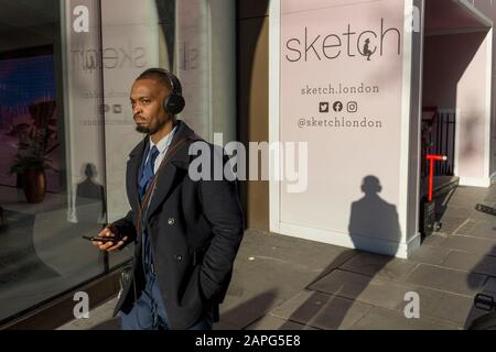 Un uomo ascolta le cuffie mentre cammina oltre 'Sketch', una gastro-galleria su Conduit Street, il 20th gennaio 2020, a Londra, Inghilterra. Foto Stock