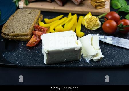 Costolette sotto salsa al miele su una tavola di legno accanto ai pomodori, peperoni e basilico con rosmarino, feta affettata con cracker. Viste dall'alto Foto Stock