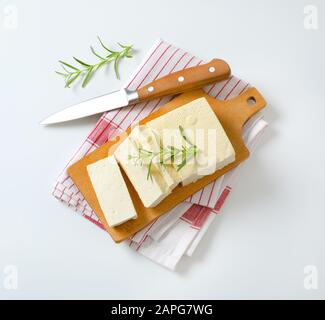 Blocco a fette di cagliata di fagioli freschi (tofu) su tagliere Foto Stock