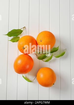 Quattro arance e foglie intere mature Foto Stock