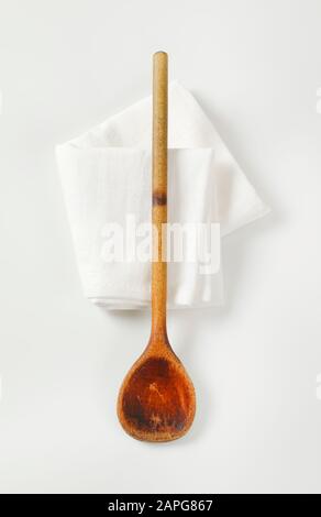 Old cottura in legno (agitazione) cucchiaio su tovagliolo bianco Foto Stock