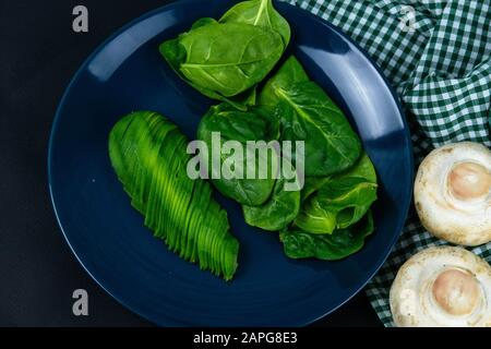 Pepe bulgaro, funghi e avocado affettato su un piatto blu, oltre alla composizione del tovagliolo nella gabbia verde bianca. Viste dall'alto Foto Stock