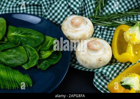 Pepe bulgaro, funghi e avocado affettato su un piatto blu, oltre alla composizione del tovagliolo nella gabbia verde bianca. Viste dall'alto Foto Stock